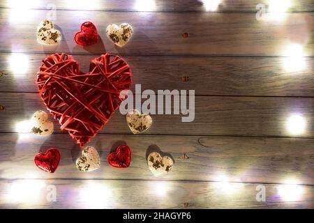 A large red wicker decorative heart on the left side and small hearts around it. There are glowing lights around the frame. On the right there is a pl Stock Photo