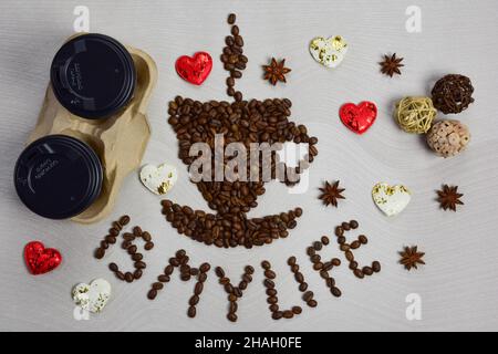 This figurine in the form of a cup of coffee with a saucer is made of coffee beans with the inscription COFFEE IS MY LIFE under it. On the left are tw Stock Photo