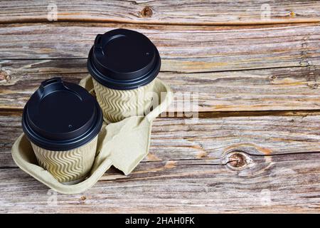Two cups of coffee from disposable glasses on a decorative stand on the left side of the frame against a background of wooden boards. Stock Photo
