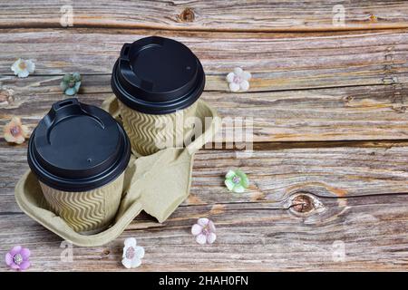 Two cups of coffee from disposable glasses on a decorative stand on the left side of the frame against a background of wooden boards. Stock Photo