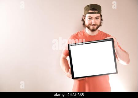 Young handsome bearded man showing blank signboard, isolated on gray background Stock Photo