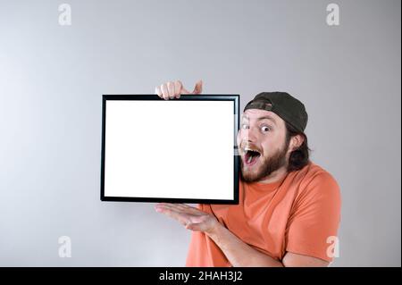 Young handsome bearded man showing blank signboard, isolated on gray background Stock Photo