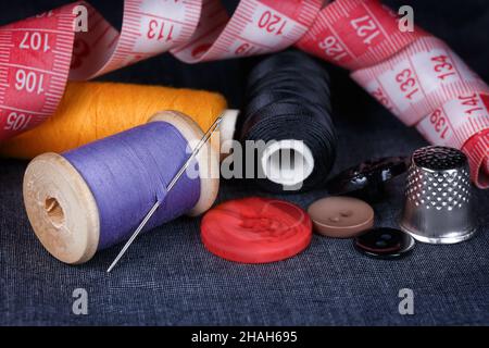 Sewing accessories close-up on a cloth basis. Needle, thread, buttons, thimble and measuring tape Stock Photo