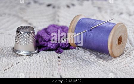 Wooden spool with thread, thimble and needle on lace Stock Photo