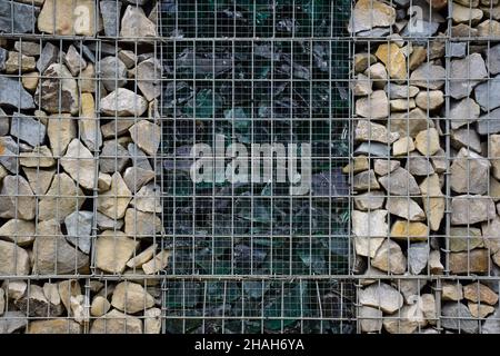 A decorative fence made of stones behind bars and broken large glass in the middle. Photographed full frame Stock Photo