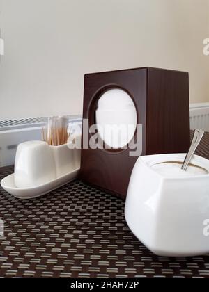 On the table in a cafe or restaurant, serving from containers for salt, sugar and pepper, a stack of toothpicks and a napkin dispenser. On the devices Stock Photo