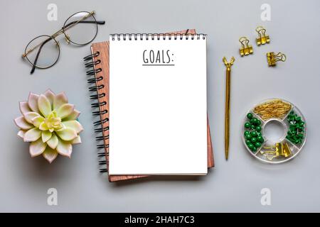 Notepad, homeplant, glasses, pen on gray background Financial planning, goals for New Year concept Top view Flat lay Finance training and strategies Stock Photo