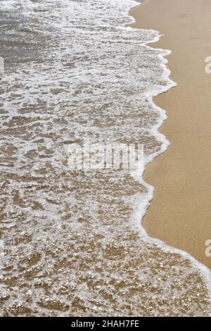 Foamy sea waves on a sandy beach. Shot from above from a high angle Stock Photo