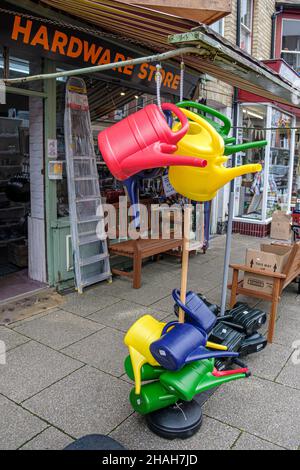 Colourful watering cans on display outside the Knillco Hardware Shop, Middleton Street, Llandrindod Wells, Powys, Wales Stock Photo