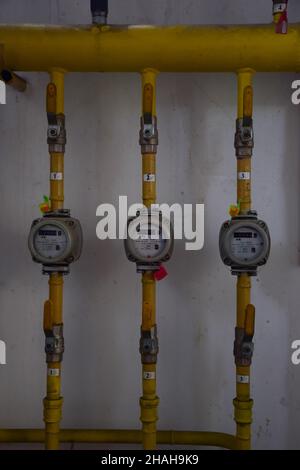 Several gas meters in a row with yellow iron pipes emanating from them and switches Stock Photo