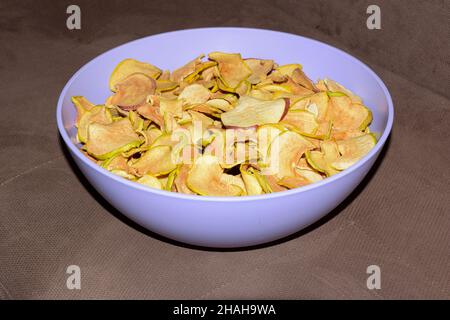 Dried slices of light apple lie in a plastic plate sprinkled with cinnamon Stock Photo