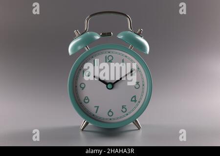 Turquoise alarm clock at ten o'clock on gray background Stock Photo