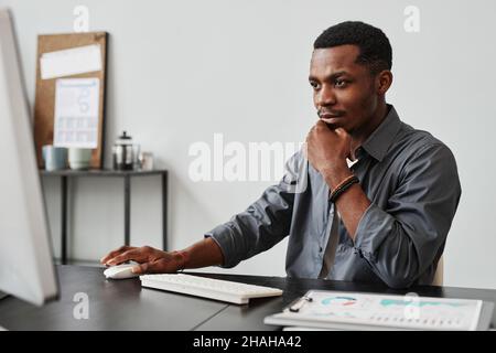 African young businessman sitting at the table and working on his computer at office Stock Photo