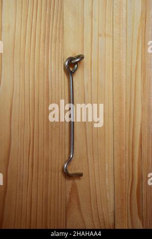 An iron hook hangs on the wooden panel of the door to close the door. The texture of the wood is clearly visible Stock Photo