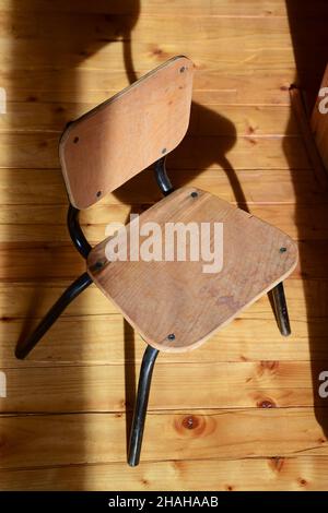 There is a small decorative wooden chair on the wooden parquet floor. Nobody sits on it. Stock Photo