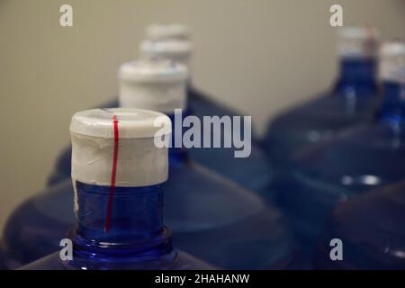 Top of large plastic bottles with filtered clean water extending in a row into perspective. The back row is blurry Stock Photo
