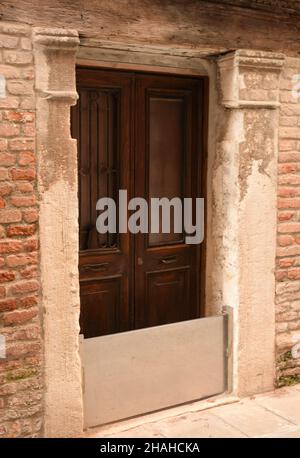 A metal barrier has been installed on the doors of an old historic brick building to trap water during a flood. Stock Photo