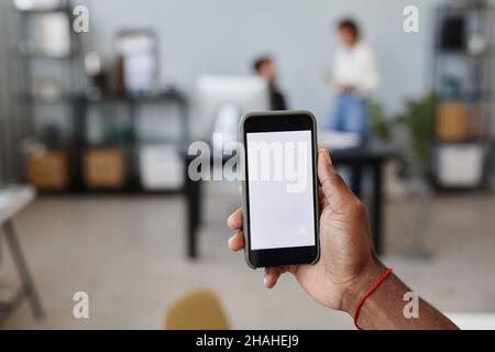 Close-up of man holding smart phone in his hand with empty screen while working at office Stock Photo