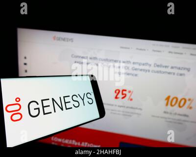 Mobile phone with logo of US software company Genesys Cloud Services Inc. on screen in front of business website. Focus on left of phone display. Stock Photo