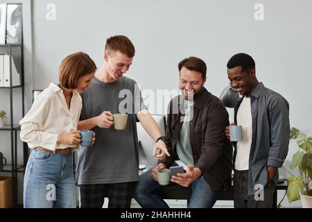 Business people using mobile phone and drinking coffee during coffee break at office Stock Photo