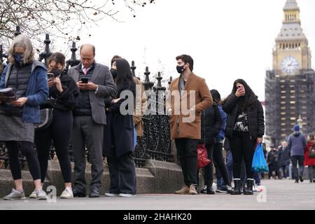 People queuing on Westminster Bridge for booster jabs at St Thomas' Hospital, London. Everyone over 18 in England will be offered booster jabs from this week, Prime Minister Boris Johnson said on Sunday night, as he declared an 'Omicron emergency'. Picture date: Monday December 13, 2021. Stock Photo