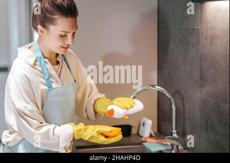Smiling woman in yellow gloves doing housework Stock Photo
