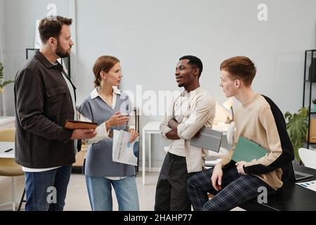 Group of young business people talking to each other and discussing new project together in team at office Stock Photo
