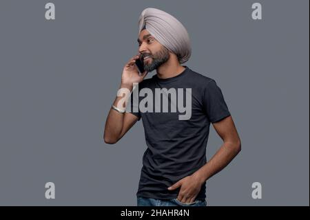 Joyous attractive Indian man having a phone conversation Stock Photo