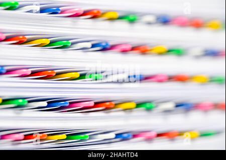 Colorful paperclips in a stack of files and papers. Office work, bureaucracy or red tape concept. Stock Photo
