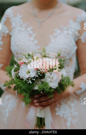 Beautiful wedding bouquet of flowers in hands of the bride. Bridal bouquet at bride's hands. Bride holding her beautiful bouquet Stock Photo