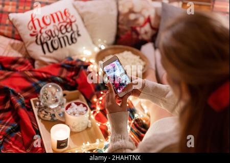 faceless candid woman holding in hand smartphone and taking video of food and drink and decor for blog. enjoyment relaxing at camping home in cozy bed Stock Photo