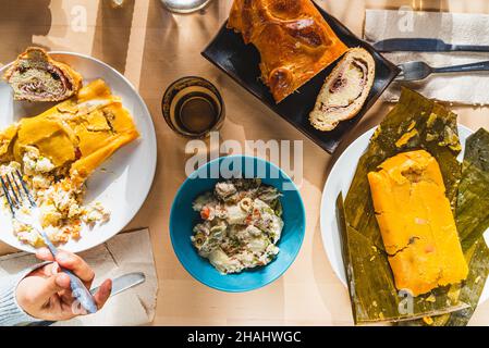 venezuelan christmas food display on table with traditional hallacas, pan de jamon or ham bread, and mixed salad, with cutlery and ready. traditional Stock Photo