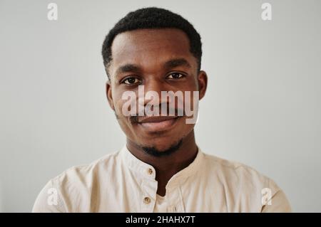 Portrait of African young man dressed in shirt looking at camera against the white wall Stock Photo