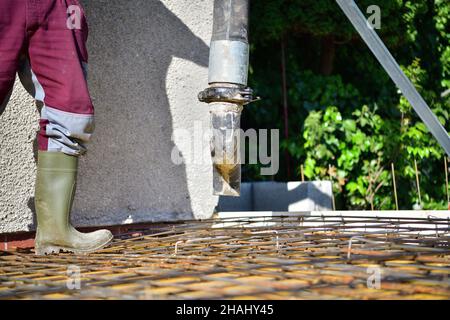 A concrete worker on a construction site concretes walls using a machine Stock Photo