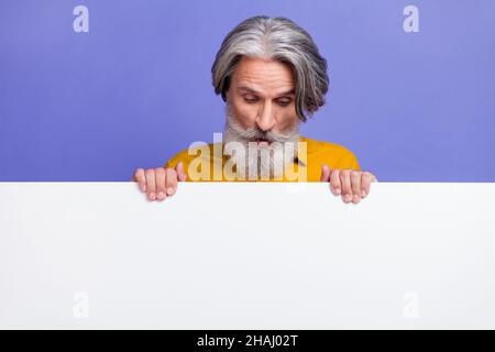 Portrait of attractive amazed gray-haired man looking copy space ad isolated over bright violet purple color background Stock Photo