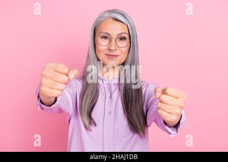 Portrait of attractive cheery focused gray-haired woman driving invisible car isolated over pink pastel color background Stock Photo