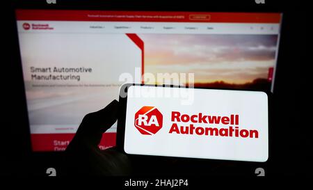 Person holding smartphone with logo of US company Rockwell Automation Inc. on screen in front of website. Focus on phone display. Stock Photo