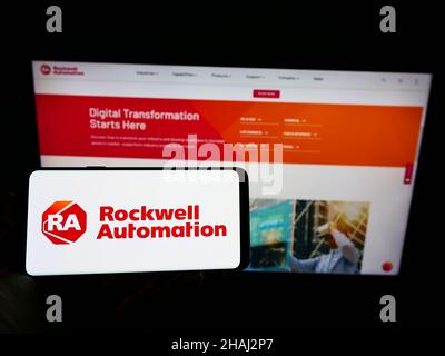 Person holding cellphone with logo of US company Rockwell Automation Inc. on screen in front of business webpage. Focus on phone display. Stock Photo