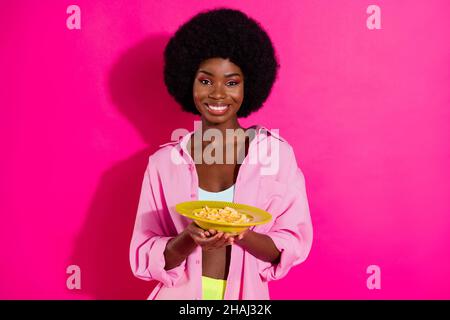 Photo of sweet shiny dark skin lady wear casual shirt eating cereals smiling isolated pink color background Stock Photo