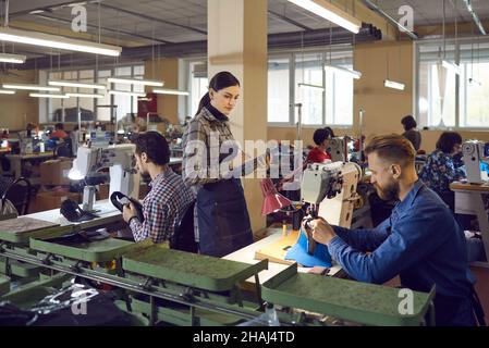Female quality controller master checking shoemaker work at shoe factory Stock Photo
