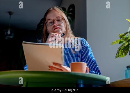Young smart woman in glasses reading book and studying in cafe. Female reader portrait. Stock Photo