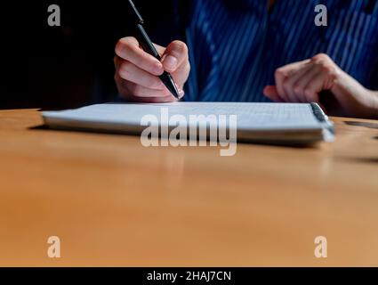 Student hands close up writing with pen in notepad or planner, taking notes on wood office desk with copy space. Stock Photo