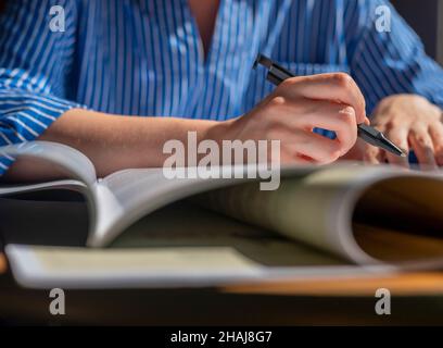Female hands with pen closeup writing in notebook, taking notes, studying. Stock Photo