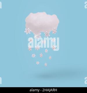 Creative concept with cloud and falling winter snowflake on bright blue background. Minimal winter holidays concept. Stock Photo