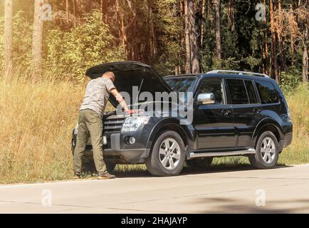 Man standing and looking in hood raised up and thinking about problem after car break. Stock Photo
