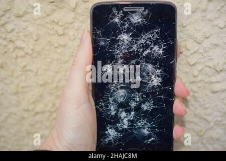 Cell phone with smashed screen in female hand. Stock Photo