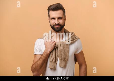 Portrait of happy smiley handsome bearded man with white t shirt posing against orange background. studio shot. Stock photo Stock Photo