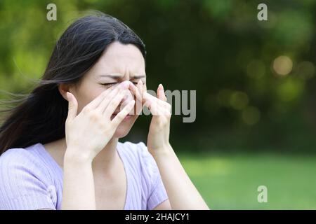 Asian woman scratching itchy eyes in a park in summer Stock Photo