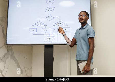 Portrait of young African-American teacher pointing at digital blackboard in coding class, copy space Stock Photo