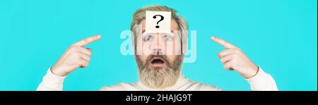 Beard man question mark in head, solution problems. Thinking man with question mark on blue background. Man with question mark on forehead looking up Stock Photo